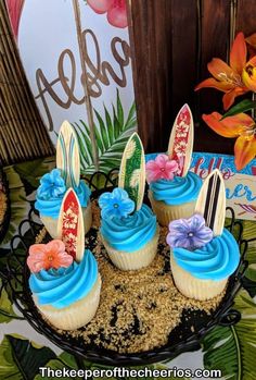 cupcakes decorated with surfboards and flowers on a plate