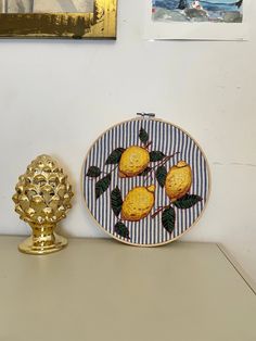 a plate with three lemons on it sitting next to a gold vase and painting