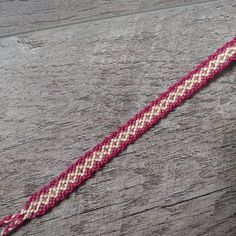 a pink and white bracelet sitting on top of a wooden table