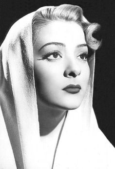 a black and white photo of a woman with a veil on her head, looking off to the side