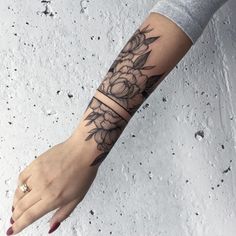 a woman's arm with a flower tattoo on the left side of her hand