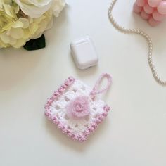 a small crocheted purse sitting next to a flower bouquet on a white table