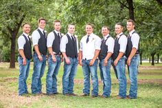 a group of young men standing next to each other in front of trees and grass