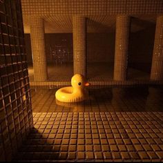 an inflatable rubber ducky sits on the floor next to a tiled wall