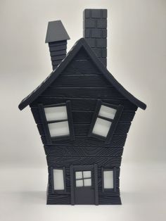 a small house made out of black paper with windows and chimneys on the top floor