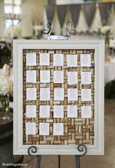 a cork board with names on it sitting in front of a table at a wedding