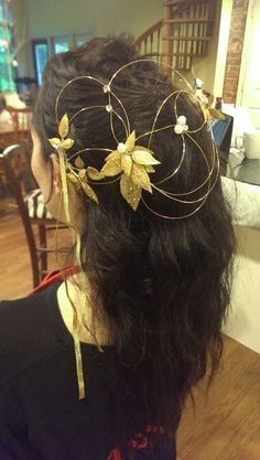 a woman with long hair wearing a gold leaf headpiece on top of her head