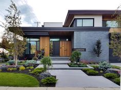 a modern house with landscaping in the front yard and walkway leading up to it's entrance