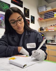 a female in a lab coat writing on a piece of paper