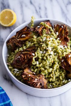 a white bowl filled with green pasta and garnished with shredded parmesan cheese