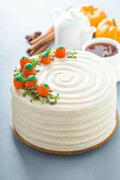 a white cake with frosting and small carrots on top, surrounded by cinnamon sticks