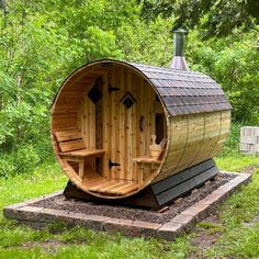 a wooden barrel sauna sitting on top of a lush green field