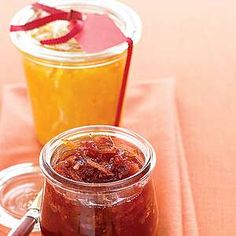 two jars filled with jam sitting on top of a table next to an orange napkin