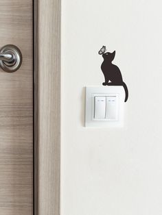 a black cat sitting on top of a light switch