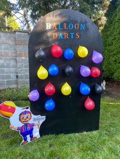 the balloon darts game is on display in the grass near a sign that says balloon darts