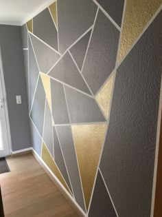 the wall is painted with gold and silver geometric designs on it, along with hardwood flooring