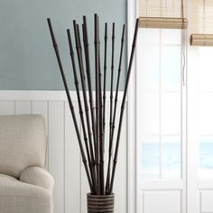 a vase with sticks in it sitting next to a chair