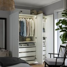 an open closet with clothes on hangers and a chair next to it in a bedroom