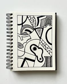 a spiral notebook with black and white drawings on the cover, sitting on a table