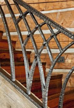 an iron and wood stair railing in front of a wooden wall