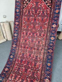 an antique persian rug is on display in a room with blue carpet and white walls