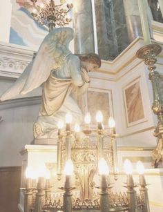 an angel statue in front of a chandelier