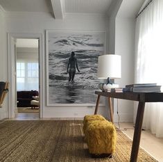 a living room with a painting on the wall next to a table and chair in front of it