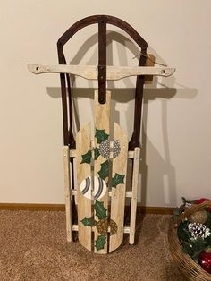 a wooden sled decorated with holly leaves and ornaments on the floor next to a basket