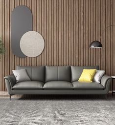 a gray couch sitting next to a wooden wall with a round mirror on the wall