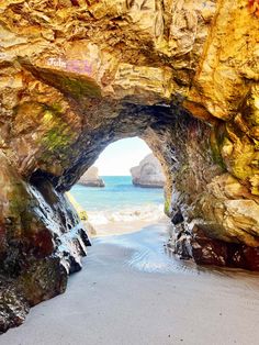 a beach with rocks and water on it's sides, as seen through an opening in the rock