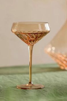 a glass filled with liquid sitting on top of a green tablecloth covered countertop