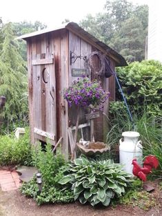 an outhouse is surrounded by plants and other things in the yard, including flowers