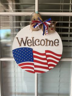 a welcome sign hanging from the side of a window with an american flag on it