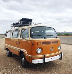 an orange van parked on top of a dirt field