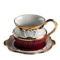 two cups and saucers with gold trimmings on the sides, one is red