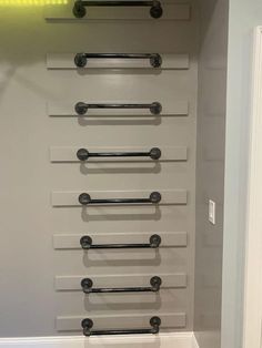 an empty bathroom with white walls and black handles on the towel rack, along with several metal bars