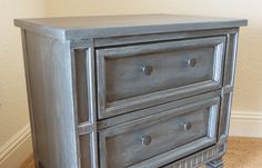 a gray dresser with three drawers in a room next to a wall and carpeted floor