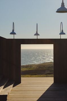 three lamps on top of a wooden structure near the ocean