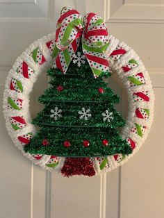 a christmas wreath hanging on the front door with a green and red tree in it