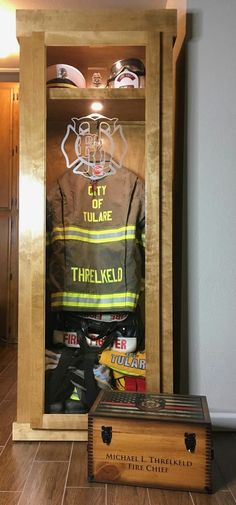 a fireman's uniform in a wooden display case next to other items on the floor