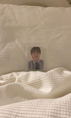 a photo of a young man is placed in the middle of an unmade bed