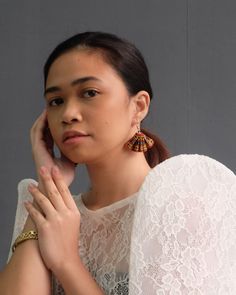 a woman with her hand on her chin and wearing large earrings, posing for the camera