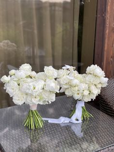 two vases with white flowers are sitting on a table