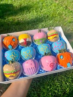 a box filled with cupcakes sitting on top of a lush green field covered in grass