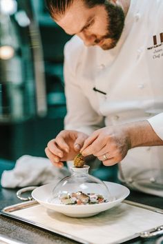 a man in a chef's uniform is preparing food on a plate