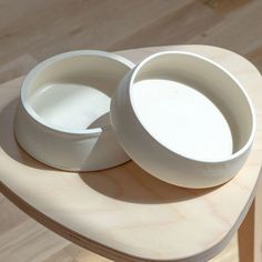 two white bowls sitting on top of a wooden table