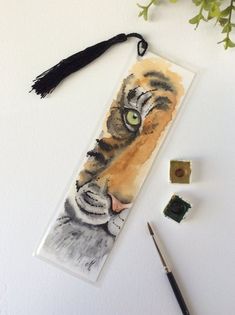 a bookmark with an image of a tiger's face on it next to flowers