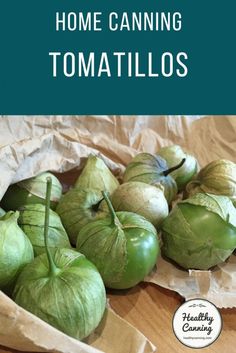 some green apples sitting on top of a wooden table next to brown paper and the words home canning tomatoes