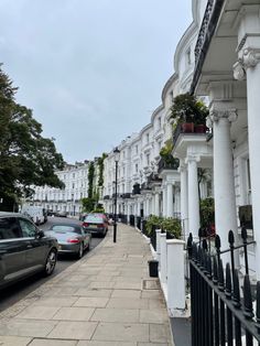 cars parked on the side of a street next to tall white buildings