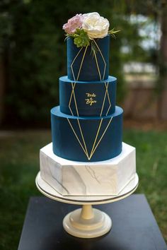 a three tiered blue and white cake with flowers on top